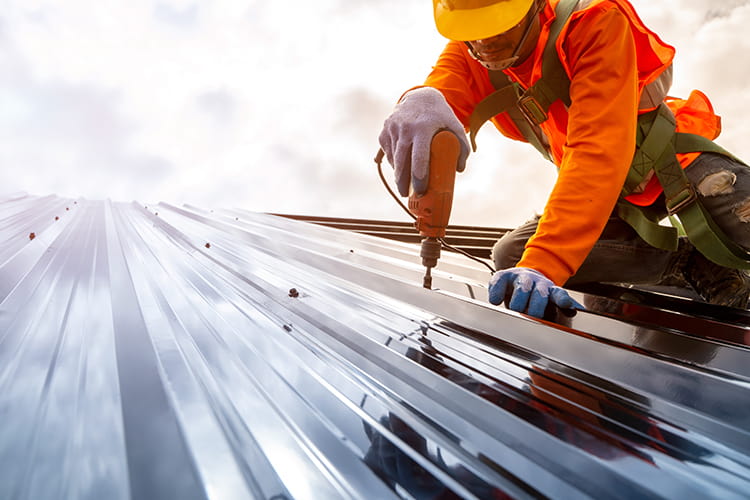 A construction worker drills on a roof